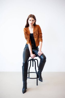 Elinde bir sandalyeyle siyah deri ceketli güzel bir kadın..