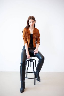 Stüdyoda sandalyede oturan deri ceketli genç kız.