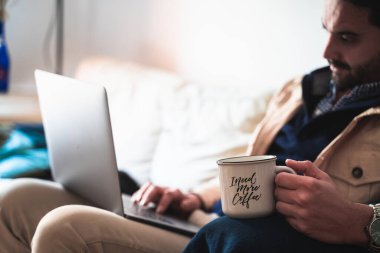 Adam evde çalışıyor, kahve içiyor.