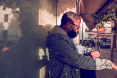 Otobüsü bekleyen maskeli siyah adam.