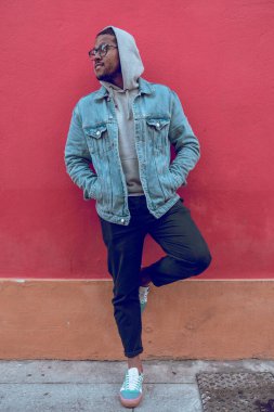 Siyah çocuk kırmızı duvarda poz veriyor.