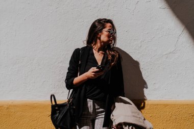 Genç bir kadın güneş altında arkadaşlarını bekliyor.