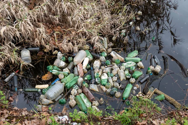 Plastic bottles and trash in a polluted river. Water contamination. Environmental pollution