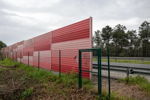 Orange noise protection wall on a freeway. Highway noise barrier. Motorway infrastructure