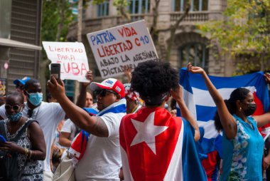 12 Temmuz 2021. Barselona, İspanya. Küba halkı Paseo de Gracia sokaklarında konsolosluğun önünde protesto yapıyor. Fidel Castro diktatörlüğüne karşı miting, bayraklar ve karteller.
