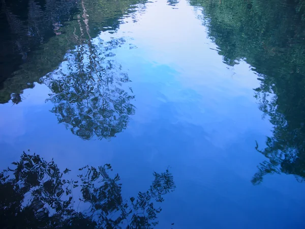 Reflexão de árvores na água, reflexão de árvores com céu azul. silhueta árvores reflexão sobre a água . — Fotografia de Stock