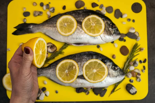 Deniz ürünleri. Limon dilimli taze dorada balığı, sarı arka planda biberiye..