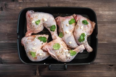 Taze tavuk bacakları ahşap bir masada sos ve baharatla marine edilmiş..