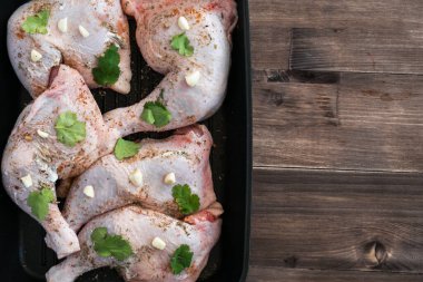 Taze tavuk bacakları ahşap bir masada sos ve baharatla marine edilmiş..