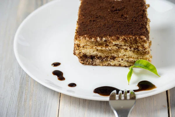 Çikolata şurubu ve ahşap arka planda beyaz tabakta tatlı Tiramisu.