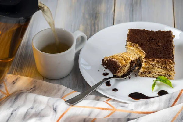 Çikolata şurubu ve ahşap arka planda beyaz tabakta tatlı Tiramisu.