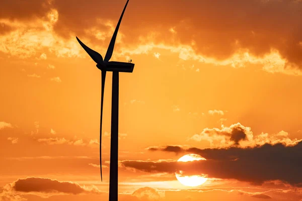 wind turbine at sunset with partly cloudy sky, wind turbine in twilight