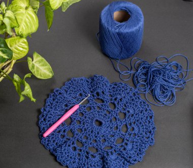 Yünden örülmüş bir parça örgü ve yün tomurcuğu mavi ve dekoratif bitkilerle örülmüş.