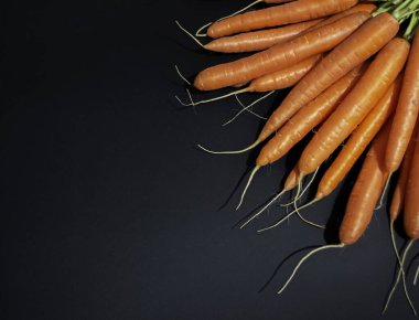 Turuncu ve siyah arka planda sağlıklı, sulu, taze havuçlar..