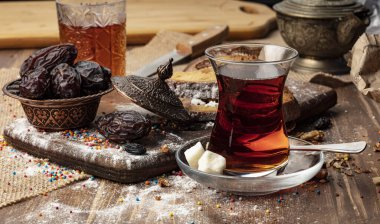 Bir fincan sıcak çay ve ahşap arka planda hurma..
