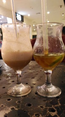 Sade bardakta buzlu kahve, berrak bardakta buzlu çay. Masadalar..