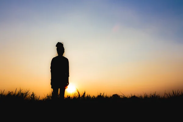 Silhouette einer Frau bei Sonnenuntergang, im Stehen, fast düstere Atmosphäre — Stockfoto