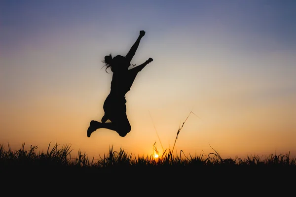 Silhouette de femme au coucher du soleil, posture de saut, près de Dim atmosphere — Photo