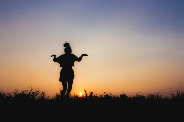 Gün batımında, atlama duruş, loş atmosfer yakınındaki kadın silüeti — Stok fotoğraf