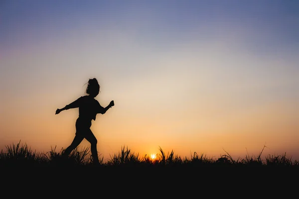 Silhouet van de vrouw bij zonsondergang, run houding, in de buurt van Dim sfeer — Stockfoto