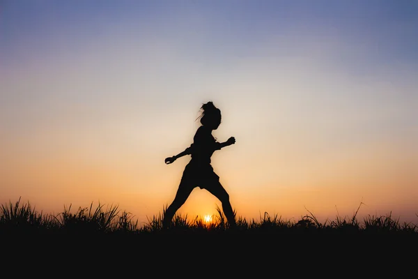 Silhouet van de vrouw bij zonsondergang, run houding, in de buurt van Dim sfeer — Stockfoto