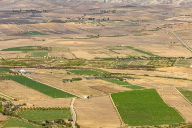 Sicilya 'da bulutlu bir gökyüzünün altında yuvarlanan tepeler ve tarlalar.