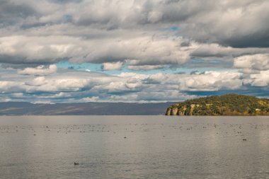 Parlak bulutlu gökyüzünün altında huzurlu göl manzarası