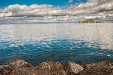 Parlak bulutlu gökyüzünün altında huzurlu göl manzarası