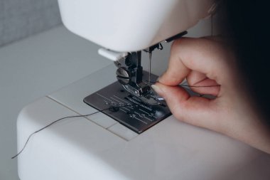 Dikiş makinesine iğne batıran bir elin yakın plan çekimi. Hobiler ve dikiş makinesi üzerinde çalışmak. Dikiş dikmek ve iş hazırlığı