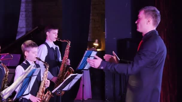 Дирижер руководит детским джаз-бэндом, выступающим на музыкальном фестивале — стоковое видео