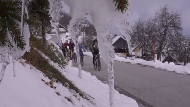 スロベニア。冬。村への道。サイクリストのグループ. — ストック動画