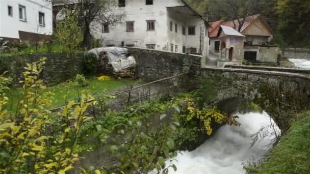 斯洛文尼亚。Kroparica 河。Kropa 村。桥和漩涡。在海岸的房子. — 图库视频影像