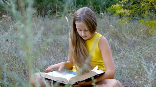 Bela jovem adolescente está lendo um livro — Vídeo de Stock