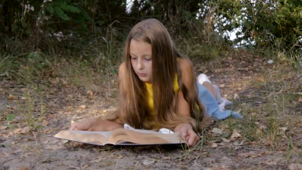 Девушка лжет и читает книгу — стоковое видео