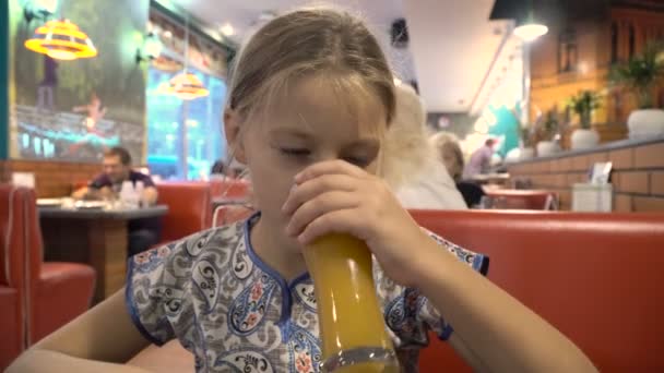 A menina está bebendo suco em um café . — Vídeo de Stock