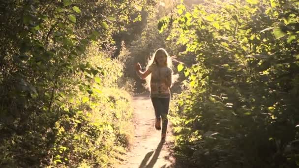 Chica corriendo por el parque bajo el sol — Vídeo de stock