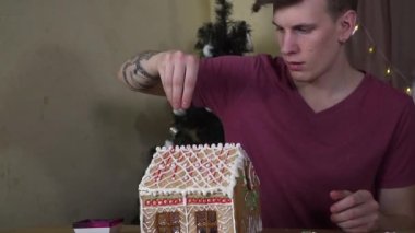 Adamın biri Noel kurabiyesi evi dekore ediyor.