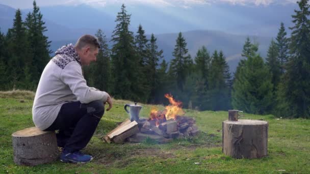 山の中の火の近くの男 — ストック動画