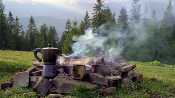 Ochtend koffie wordt gekookt in een koffiezetapparaat op een vuur in de bergen — Stockvideo