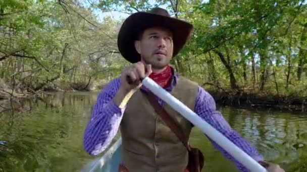 Cowboy in een kano drijft op de rivier — Stockvideo