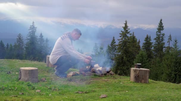 Dağlarda ateşin yanında bir adam — Stok video