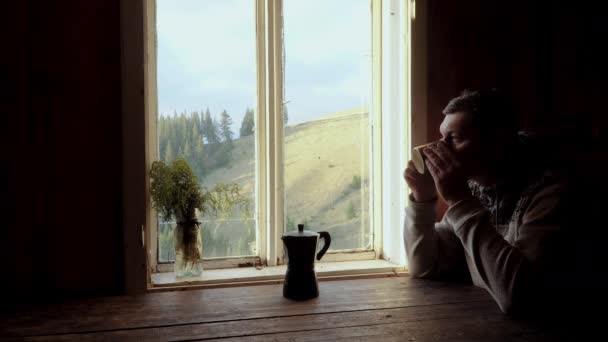 Un hombre bebe café cerca de una ventana — Vídeos de Stock