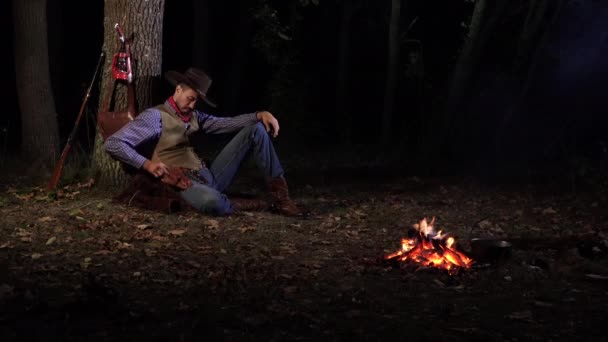 Vaquero cerca del fuego en el bosque por la noche — Vídeos de Stock
