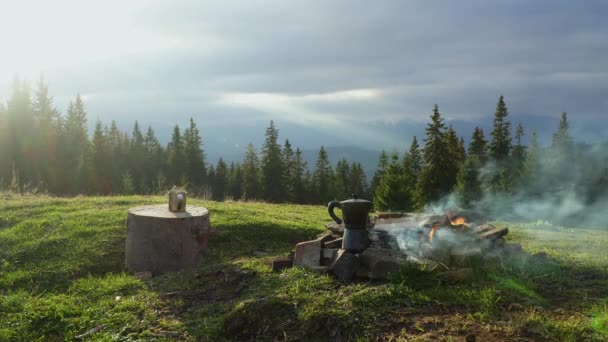 Kaffeebecher und Kaffeemaschine am Feuer in den Bergen — Stockvideo