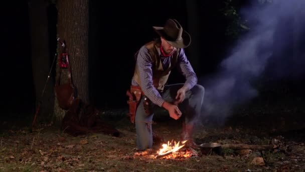 Cowboy perto do fogo na floresta à noite — Vídeo de Stock