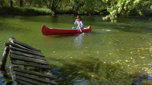 Vaquero en una canoa flota en el río en el bosque — Vídeos de Stock