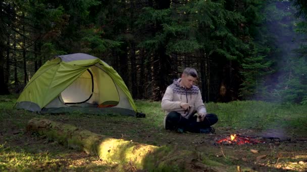 Seorang pria minum kopi dekat tenda di hutan — Stok Video