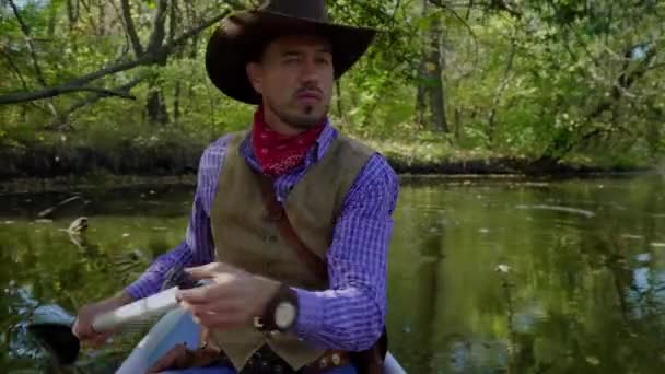 Cowboy in een kano drijft op de rivier — Stockvideo