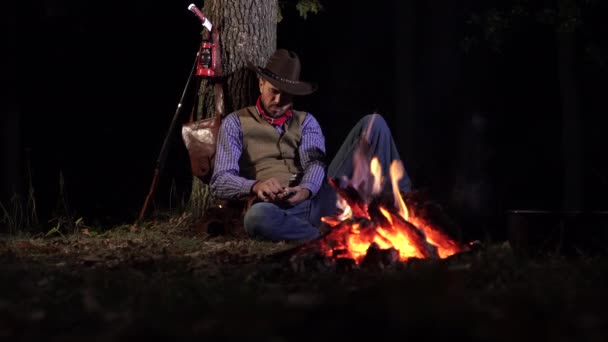 Cowboy nära brasan i skogen på natten — Stockvideo