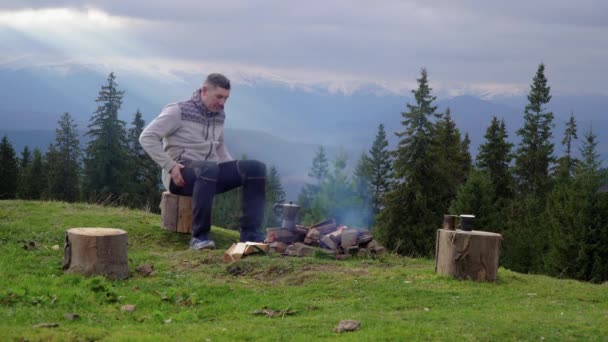 Um homem perto de um fogo nas montanhas — Vídeo de Stock